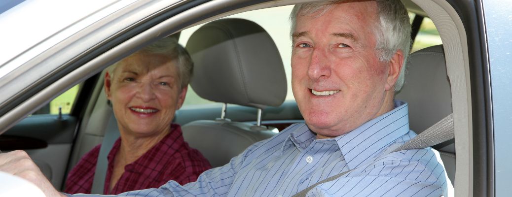A couple wearing seatbelts and smiling